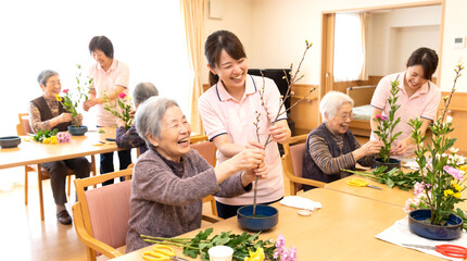 Obraz premium 生け花を一緒に楽しむスタッフと利用者