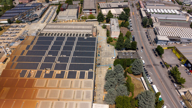 Aerial view of an industrial district near Linate Airport featuring warehouse buildings with solar panels, surrounding roads, and urban infrastructure in Peschiera Borromeo, Lombardy, Italy.