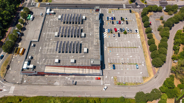 Aerial view of the Pittarello building featuring extensive solar panel arrays on the roof and a spacious parking lot in Peschiera Borromeo, Lombardia, Italy.