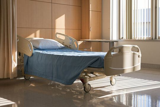 A neat hospital room features an empty medical bed bathed in soft morning light. This professional healthcare setting is ideal for medical and clinical design themes.