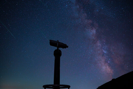 Silhouette of a observation binocular telescope under the Milky Way galaxy and shooting star meteor trails in the night sky at Babin Zub peak in Stara Planina reserve, Serbia.