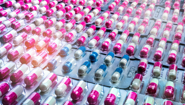 Antibiotic capsules in blister packs in large quantity for pharmaceutical supply. Antimicrobial resistance risk and responsible drug use in global healthcare system. Pharmaceutical production storage.