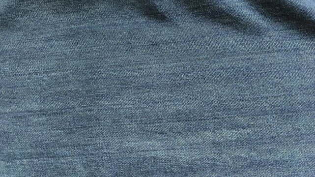 Closeup of hand fingers touch and feel old vintage or retro design blue jean cotton cloth fabric surface for checking or examining quality. Clothing or textile business concept.