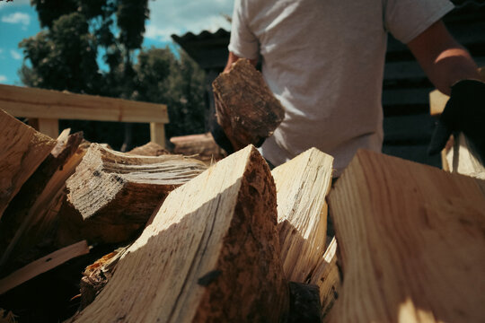 Man stacking chopped firewood into wooden crate outdoors in backyard
