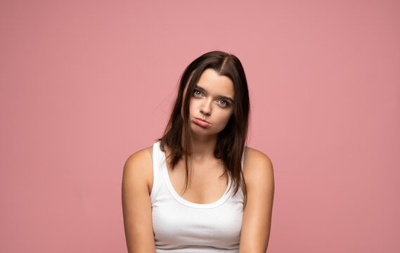 Young woman feeling unmotivated and sluggish, expressing disinterest and weariness with a pout, posing for a portrait