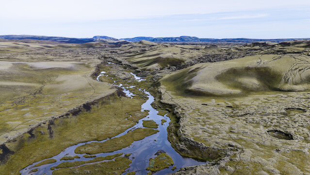 Aerial view of Laki volcanic landscape with a winding river flowing through moss-covered lava fields in Skaftarhreppur, Iceland.