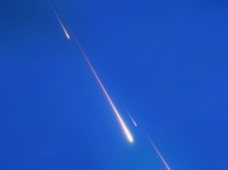 Fireballs in daylight. Beautiful bolides in the morning. Fall of bright meteorites on a blue background. © Nazarii