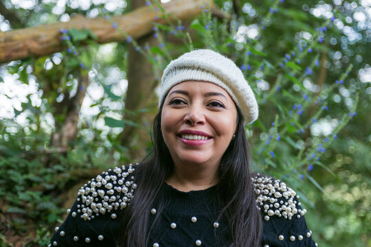 Smiling Woman Wearing a Knitted Beret in a Green Outdoor Setting