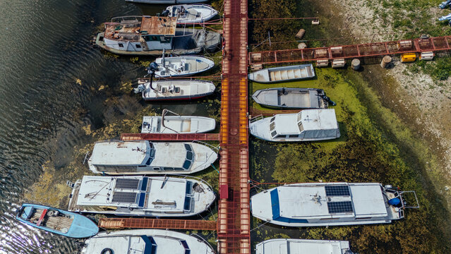 Aerial view of boats moored at the Ribarsko ostrvo pier surrounded by green algae in the Danube river in Novi Sad, Vojvodina, Serbia.