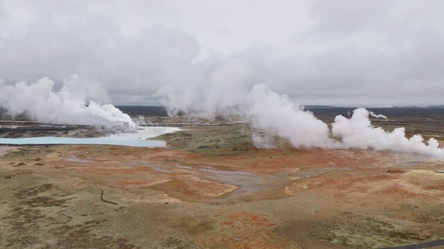 Reykjanes geothermal field releases dense steam across mineral altered volcanic terrain and shallow ponds near Reykjanes, Iceland, captured in a drone forward flyover.
