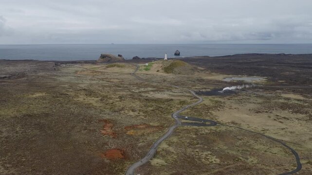 Reykjanesviti Lighthouse stands above volcanic terrain and geothermal vents near Gunnuhver, Reykjanes, Iceland, captured during a drone forward flyover.