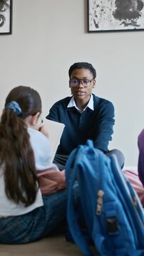 Vertical shot of African American male educator talking to school children sitting on floor in art gallery. Video is ideal for educational marketing and museum program promotions