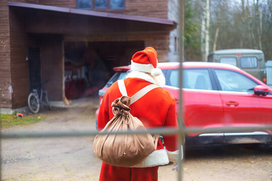 Authentic Santa Claus near a red car.
