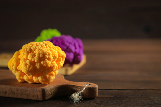 Multicolored cauliflower on a wooden table. Purple, yellow, and green florets.