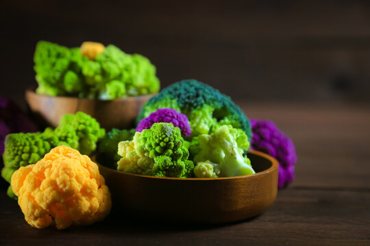 Multicolored cauliflower on a wooden table. Purple, yellow, and green florets. Rustic still life.