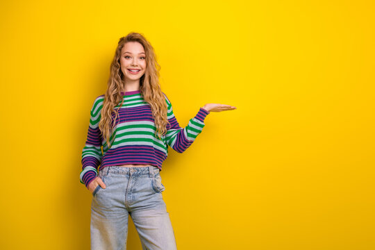 Young woman poses in a colorful striped sweater against a bright yellow background for lifestyle fashion advertising and cheerful casual promotional shot