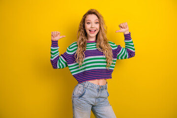 Naklejka na ściany i meble Young woman in striped sweater smiles against yellow background promoting casual fashion lifestyle