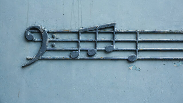 Architectural relief of bass clef and music notes on stucco wall