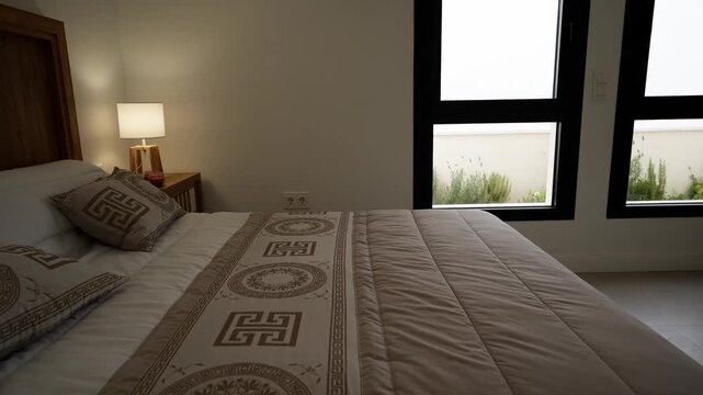 Modern bedroom interior featuring cozy double bed with neutral tone bedding and wooden headboard furniture inside minimalist house.