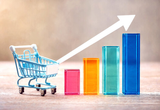Miniature shopping cart with colorful ascending bar chart showing growth in sales and business success concept