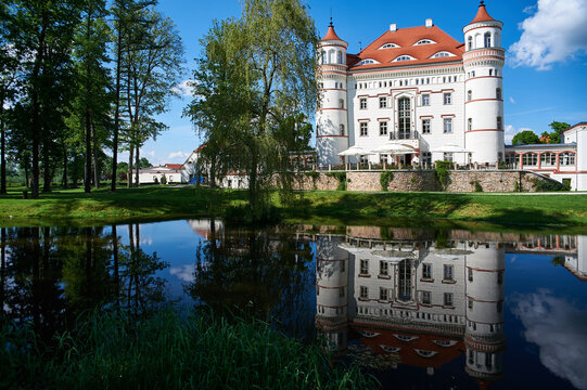 Reflection of Wojanow Castle facade and corner towers in the calm water of a pond during summer in Wojanow, Lower Silesia, Poland