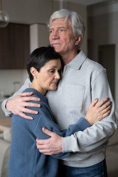 Tired mature wife being tightly embraced by husband, seeking comfort and emotional support. Loving elderly couple facing emotional distress, exhaustion, family crisis and life challenges. 