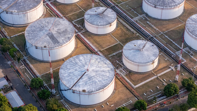 Aerial view of large white oil storage tanks in an industrial facility with connecting pipelines and surrounding greenery in Central Java, Indonesia.