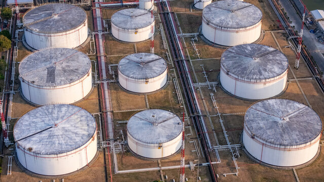 Aerial view of large industrial oil storage tanks connected by a network of pipelines in a facility in Central Java, Indonesia.