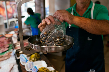 Fishmonger weighing fresh mussels at a seafood market © karrastock
