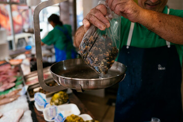 Fishmonger weighing fresh barnacles at a local market. © karrastock