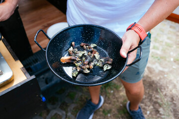 Person holding pan with goose barnacles for outdoor cooking © karrastock