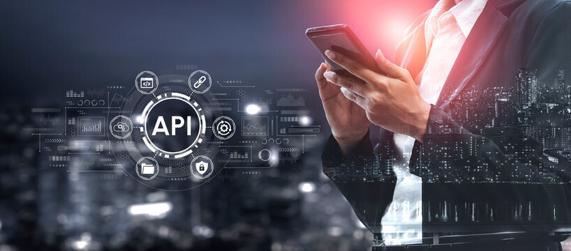 Business Professional Using Mobile Device Overlaid with Digital API Graphics in Urban Night Cityscape Background. Entropy.