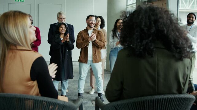 Group of professionals in a corporate setting clapping and smiling, showing appreciation and enthusiasm during a business event or conference.