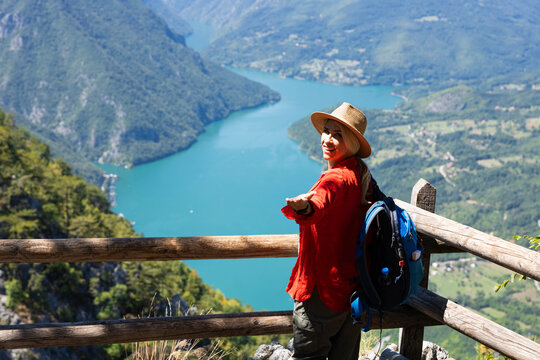 Happy woman hiker standing on banjska stena viewpoint, enjoying the spectacular drina river canyon and surrounding nature