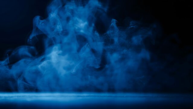 Blue smoke or fog swirling on a dark background for Halloween or horror atmosphere.