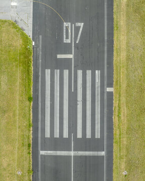 Aerial view of Landebahn Neubiberg runway with asphalt markings and numbered threshold in a grassy field in Unterhaching, Bavaria, Germany.