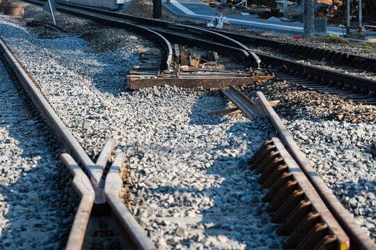 A newly installed railway switch (points) on a railroad line under reconstruction, filled with fresh grey ballast stones.