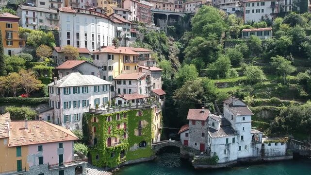 Lake Como, Italy, drone view over Nesso with colourful houses, stone bridge and green hills