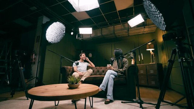 Man and woman recording a podcast in a professional studio. Two speakers discussing and broadcasting their conversation on a live streaming