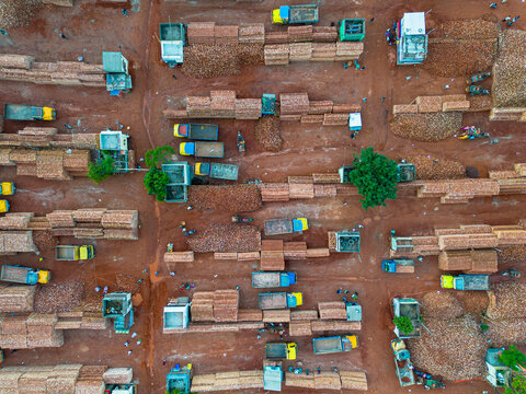 Aerial view of a busy lumber yard with stacks of wood, trucks loading timber, and workers moving around the industrial site in Dhaka, Dhaka Division, Bangladesh.