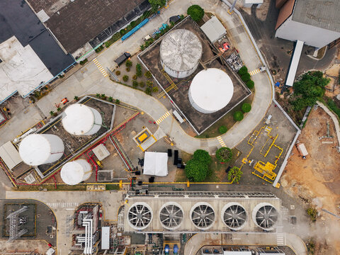 Aerial view of Parque Electrico Los Mina featuring large white storage tanks, industrial cooling fans, and paved pathways within the facility in Santo Domingo, Santo Domingo, Dominican Republic.