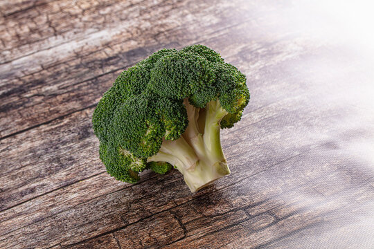Fresh broccoli head on rustic wooden surface with soft natural lighting