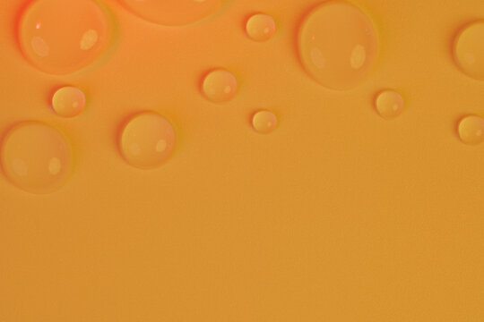 Macro shot of soft round water drops on a warm amber orange textured surface with copy space. Perfect for nourishing cosmetics, honey serum, sea buckthorn oil, skincare banner, and spa product layout.