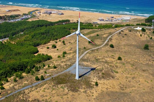 Aerial view of a single wind turbine standing on a grassy hill overlooking the Black Sea coastline in Sariyer, Istanbul, Turkey.