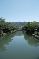 Fototapeta premium 京都の水路から望む山並みと緑豊かな初夏の風景
