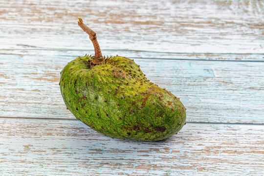 Green soursop fruit on weathered wooden surface