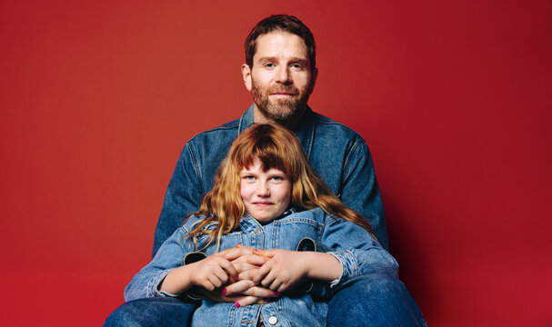Sitting together, father and daughter show a close family bond in the studio