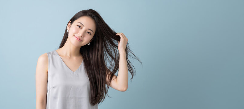 手ぐしで髪を整えながらカメラに優しい視線を向ける女性