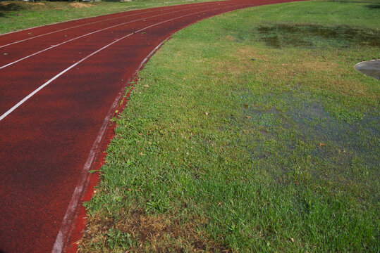 Athletics track after heavy rain with flooded grass, making outdoor training difficult in autumn