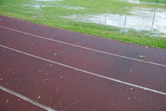 Athletics track after heavy rain with flooded grass, making outdoor training difficult in autumn